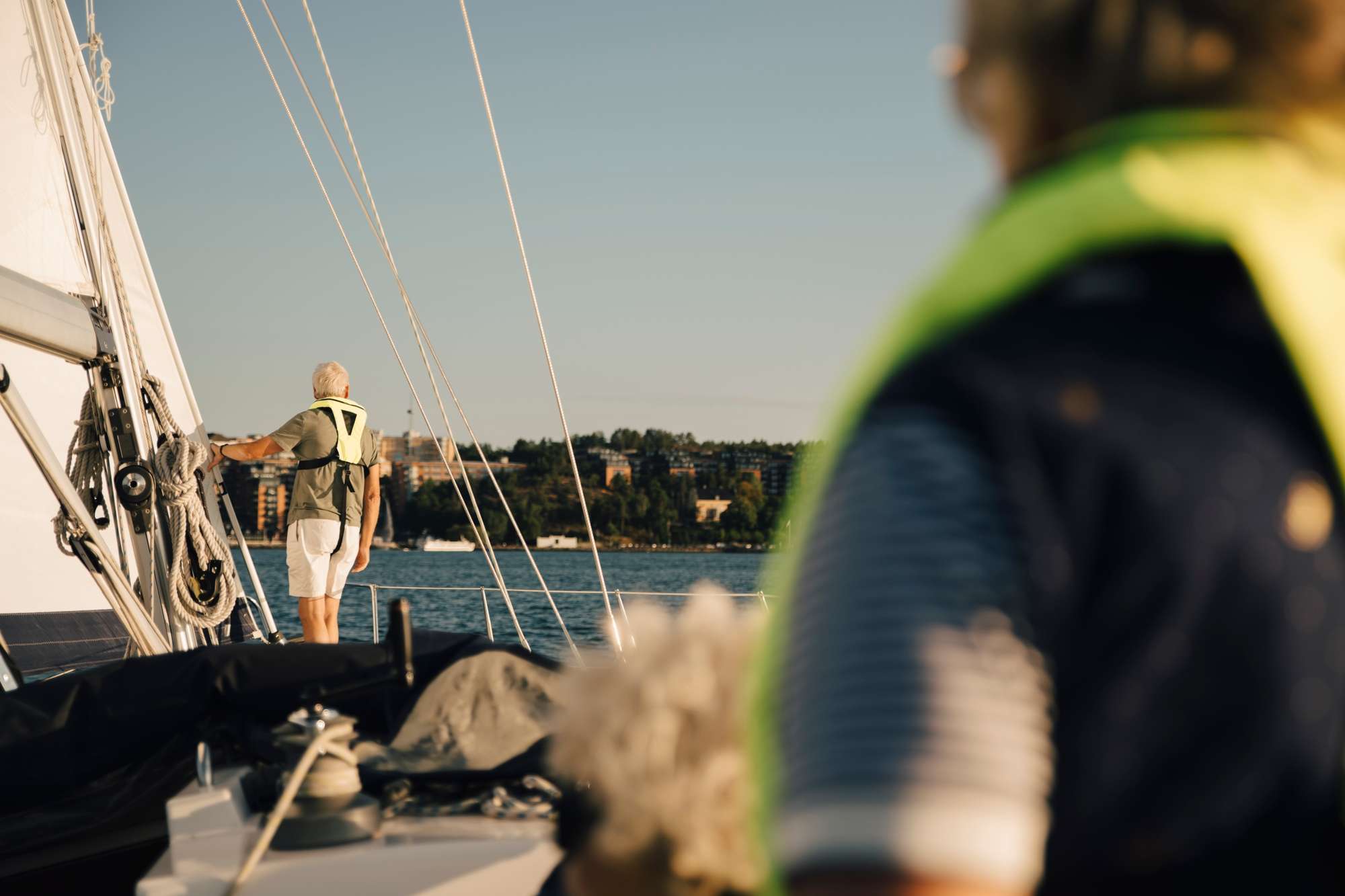 Segelbåt i Stockholm med minst två personer ombord som har gula flytvästar på sig.